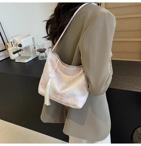 Dettaglio della borsa a secchiello jacquard champagne con motivo e nappa bianca