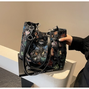 Detailed close-up of butterfly embroidery and Fashion Bags patch on the black tote bag