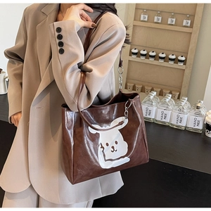Close-up of a large dark brown tote bag with a cute white rabbit print and chain strap