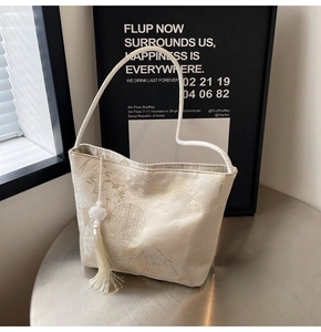 Dettaglio della borsa a secchiello jacquard beige con ricami e nappa di seta