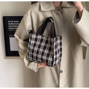 Detail of a chic checkered tote bag held by a model against a minimalist background