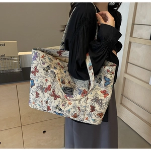 Side view of a large canvas tote bag with colorful butterfly prints on a model