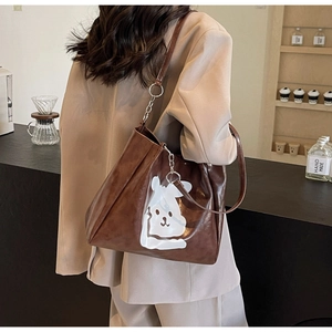 Detail of a large coffee-brown tote bag with a white cartoon rabbit and metal chain strap