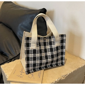 Close-up detail of black and white checkered tote bag with reinforced canvas handles