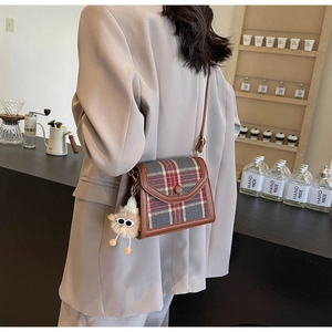 British style plaid crossbody bag with brown leather trim and funny plush charm on model
