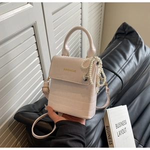 Detail of cream crocodile pattern handbag with pearl chain and gold brand logo