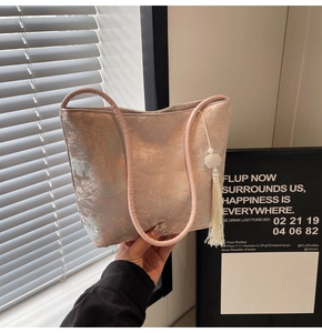 Dettaglio della borsa a secchiello in jacquard rosa con motivo tradizionale e nappa decorativa