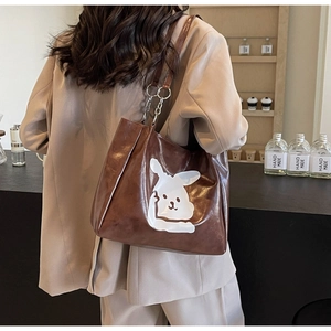Brown cartoon rabbit tote bag with metal chain strap shown worn over the shoulder