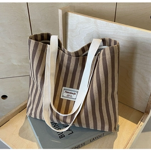 Makro-Detail der braun gestreiften Cord-Tasche mit Baumwollgriffen und Markenetikett