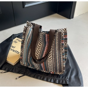 Detail of bohemian woven tote bag with geometric patterns and broad canvas shoulder strap