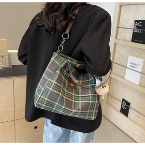 Detail of checkered tote bag with leather straps and a cute plush ball charm accessory