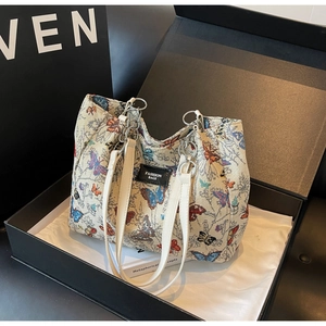 Detail of butterfly embroidery on a cream shoulder bag with polished metal rings