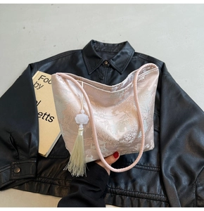 Dettaglio borsa a secchiello in raso rosa con ricami orientali e nappa decorata