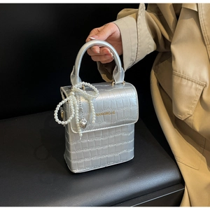 Detail of silver crocodile pattern handbag with pearl handle and heart pendant charm