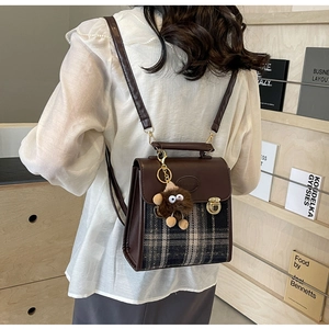 Detailed view of vintage brown checkered backpack with metallic buckle and plush charm
