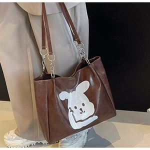 Detailed side view of large brown tote bag with white cartoon rabbit and chain strap