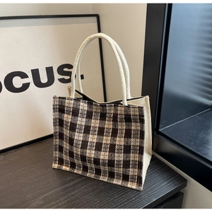 Detailed shot of a brown plaid tote bag with rope handles and a secure snap button closure