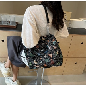 Detail of black canvas tote bag featuring vibrant butterfly embroidery and faux leather strap