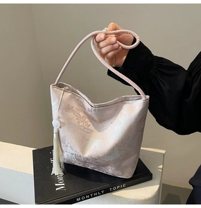 Dettaglio della borsa a secchiello in jacquard rosa con ricami e nappa di seta morbida