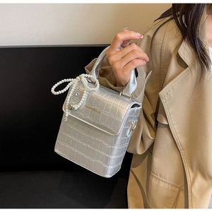 Detail of silver crocodile pattern handbag with pearl handle and metal heart pendant