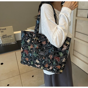 Detail of large black canvas tote bag with colorful butterfly patterns and woven label