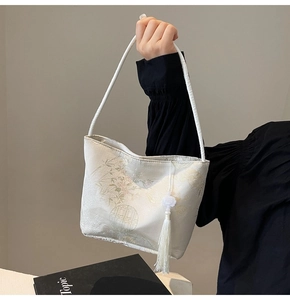 Dettaglio del tessuto jacquard bianco con motivo a montagna e nappa decorativa sulla borsa