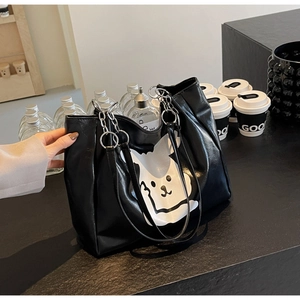 Detail of black PU leather tote bag with white cartoon print and silver chain straps