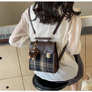 Detail of retro plaid patchwork backpack featuring a plush bear charm and chain strap