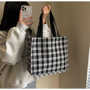 Fashionable black and white checkered tote bag with wide straps shown by a model