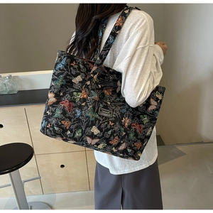 Close-up of black canvas tote bag with colorful butterfly embroidery and fashion patch