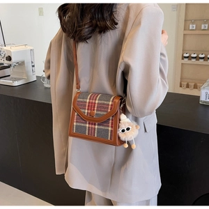 British style checkered crossbody bag with plush charm shown in a cozy cafe setting