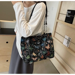 Detail of vintage tote bag featuring colorful butterfly embroidery and chain strap