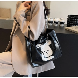 Detail of black glossy PU leather tote bag with large white cartoon dog print