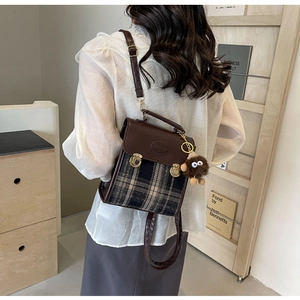Detail view of a vintage plaid crossbody bag featuring a plush monster charm on the side