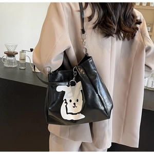 Detail of black glossy tote bag with white cartoon rabbit print and silver ring hardware