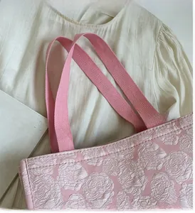 Détail du sac cabas rose avec texture de roses en relief et anses tissées solides