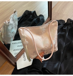 Dettaglio del ricamo e della nappa di perle su una borsa a secchiello in raso rosa