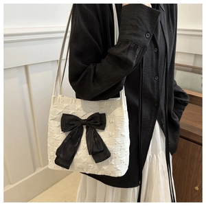 Detail of white star-textured tote bag with a large decorative black satin bow