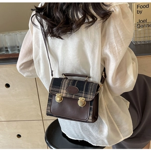 Detail of the vintage plaid and brown leather messenger bag with gold metal buckles