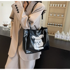 Side view of large black glossy tote bag with cartoon rabbit print on a model