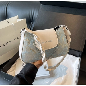 Détail du sac à épaule en jacquard bleu clair avec chaîne argentée et bandoulière