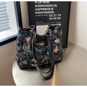 Close-up of a woven butterfly pattern tote bag with leather handles and metal rings