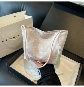 Dettaglio della borsa tote in broccato rosa con motivo jacquard e nappa floreale