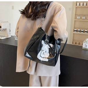 Close-up of a black PU leather tote bag with a white cartoon rabbit and metal chain strap