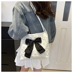 Close-up of white star-textured tote bag featuring a large decorative black bow detail