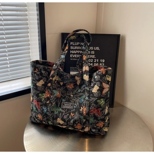Detail of a black canvas tote with vibrant butterfly embroidery and fashion label