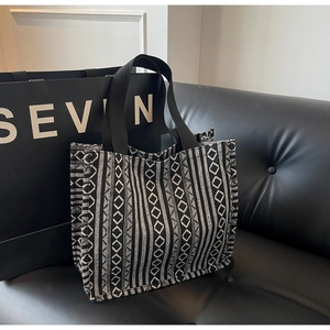 Close-up of woven geometric pattern tote bag with bohemian ethnic style on leather sofa