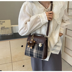 Detail of vintage plaid crossbody bag with brown leather trim and a cute plush charm