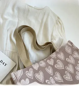 Close-up of heart pattern canvas tote bag with reinforced handles on white fabric