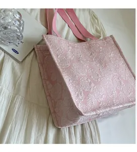 Gros plan sur le tissu jacquard à roses roses et les poignées tissées d'un grand cabas